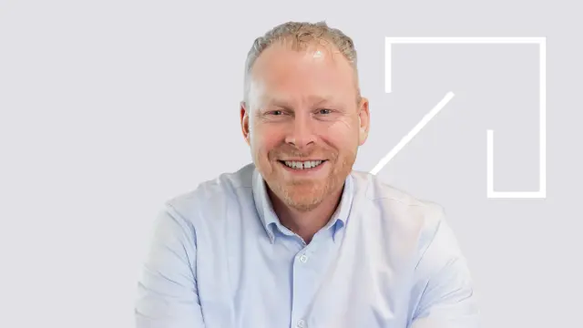 Bosch-Mitarbeiter Bernhard Gijzen im Schneidersitz vor Bosch-Logo am Standort Nieuwegein