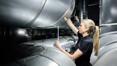Sabrina Ruis measures the distance between the pipe axles in the central energy supply plant with a meter stick