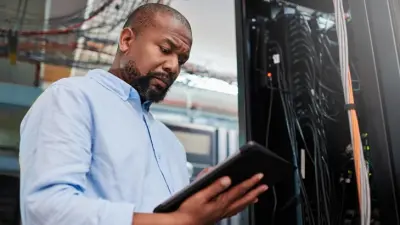 Mann steht mit einem Tablet vor einem Schaltkasten