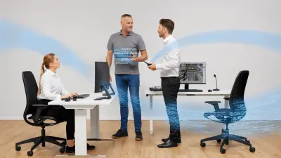 Eine sitzende Frau und zwei stehende Männer sprechen in einer Sicherheitszentrale