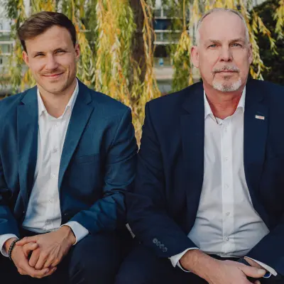 Felix Weidinger und Jens Jürgensen sitzen nebeneinander und blicken in die Kamera