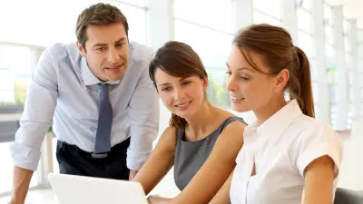 Drei Personen im Büro schauen auf Laptop Bildschirm