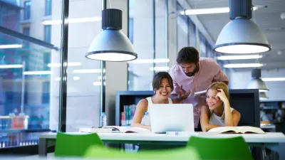 Drei Studenten haben Spaß beim Lernen in der Bibliothek