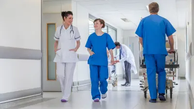 Klinikpersonal und ein Patient im Rollstuhl auf dem Flur einer Klinikstation