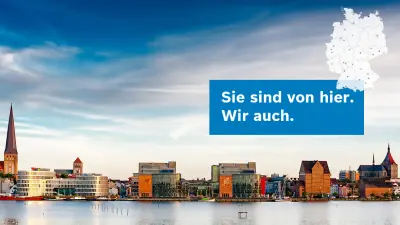 Gebäude am Flussufer mit Text im Bild: Sie sind von hier - Wir auch