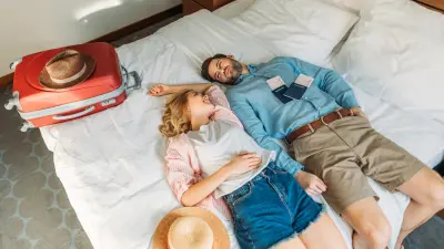 Glückliches, junges Paar mit Koffer im Hotelzimmer