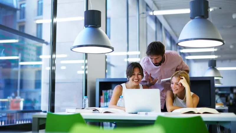 Drei Studenten haben Spaß beim Lernen in der Bibliothek