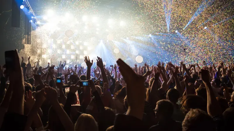 Große Gruppe Menschen feiert bei einem Konzert in einer Veranstaltungshalle