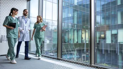 Gruppe junger Ärzte in Arztkitteln laufen durch den Klinikflur und besprechen sich