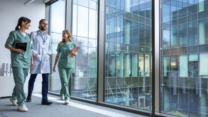 Gruppe junger Ärzte in Arztkitteln laufen durch den Klinikflur und besprechen sich