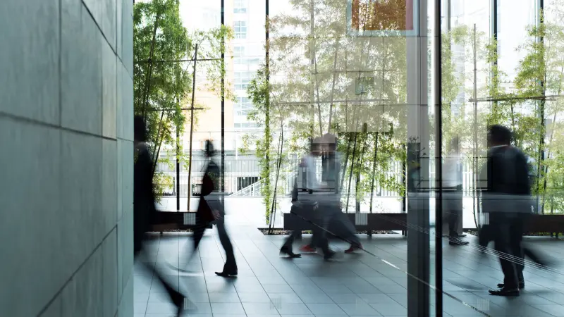 Geschäftsleute durchqueren ein städtisches Gebäude in unterschiedliche Richtungen