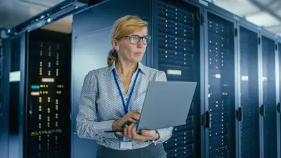 Eine IT-Mitarbeiterin steht mit einem Notebook in einem Rechenzentrum