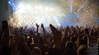 Große Gruppe Menschen feiert bei einem Konzert in einer Veranstaltungshalle