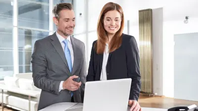 Mann und Frau mit Laptop am Stehpult