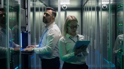 Mann und Frau mit Laptop stehen im Aufzug