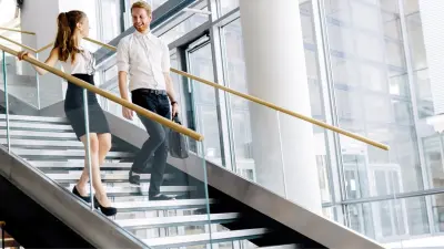 Zwei Kollegen laufen in einem Gebäude eine Treppe herunter