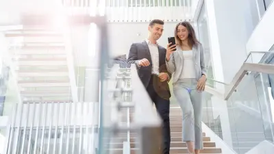 Ein Mann und eine Frau stehen auf einer Treppe und schauen auf ein Smartphone