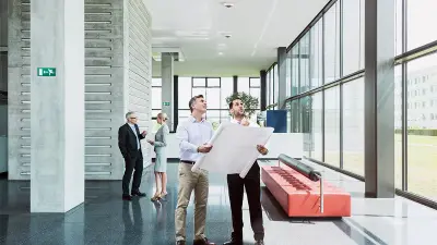 Eingangsbereich eines Gebäudes, zwei Männer besprechen die Installation von Brandmeldern an der Decke