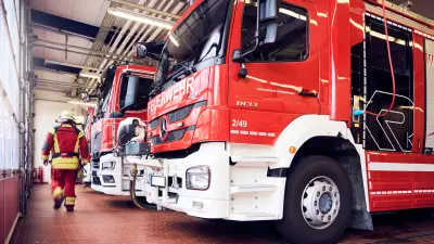 Feuerwehrmann geht neben Einsatzfahrzeugen in Gerätehaus