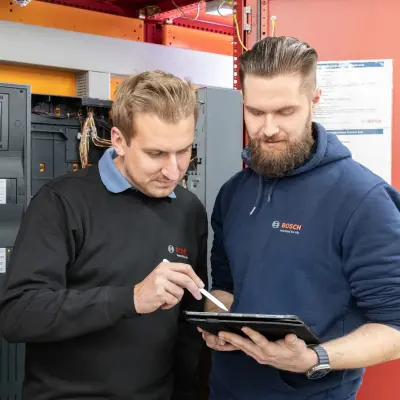 Zwei Personen beraten vor einem Schaltkasten über den Einsatz von Brandmeldetechnik