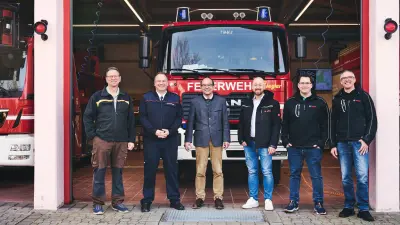 Gruppe steht vor einer Feuerwache, im Hintergrund ein Feuerwehrfahzeug