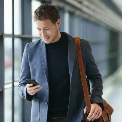 Mann mit Smartphone in der Hand auf dem Flur vor Fensterfront