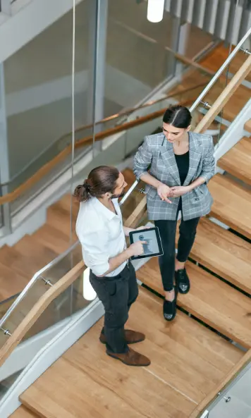 Zwei Personen unterhalten sich auf einer Treppe über Gebäudesicherheit