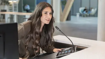Mitarbeiterin an einem Empfang spricht in das Mikrofon der Bosch Sprachalamierungsanlage PRAESENSA