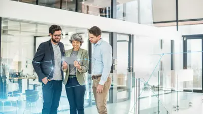 Drei Personen schauen auf ein Tablet mit intelligenter HR-Software