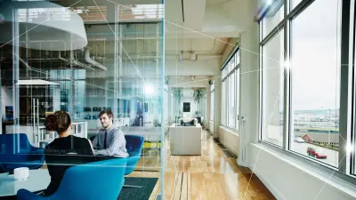 Two colleagues sitting in connected office and chatting