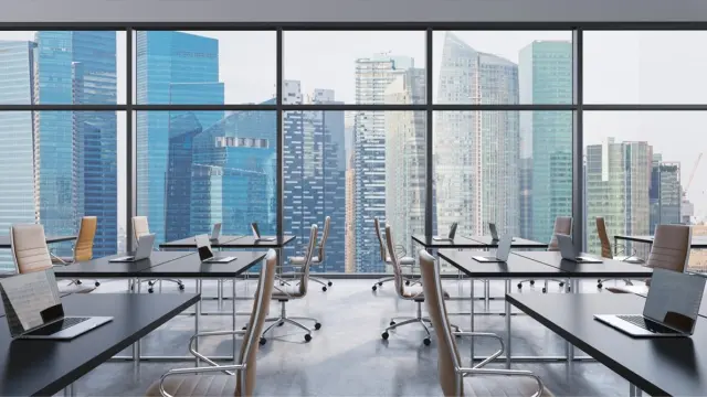 Deserted meeting room with several desks and a view of a skyline