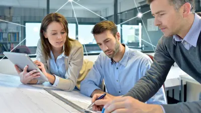 Drei Personen schauen sich gemeinsam einen Plan an