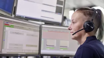 Bosch Notruf- und Serviceleitstelle, Mitarbeiterin mit Headset und Monitoren