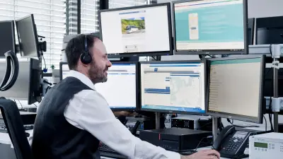 Die Bosch Notruf- und Serviceleitstelle, Mitarbeiter an seinem Arbeitsplatz mit Headset und vielen Monitoren