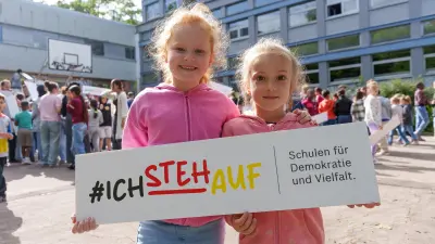 Zwei Schülerinnen mit Plakat „#ichstehauf, auf Schulgelände