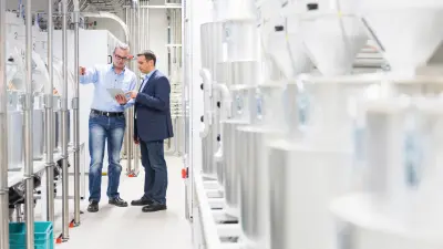 Geschäftsmann und Produktionsmitarbeiter besprechen sich in der Produktion eines Fertigungsunternehmens.