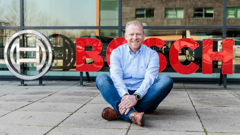 Bosch associate Bernhard Gijzen sitting cross-legged in front of the Bosch logo at the Nieuwegein location.