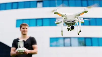 Mann steuert Drohne vor einem Gebäude