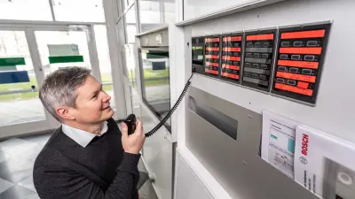 Michael Huck speaks into the microphone next to the firefighter tableau