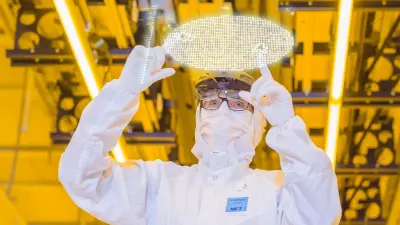 Employee checks semiconductor production in the clean room