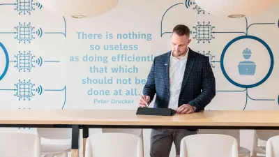 Marius Kaiser jots down something on the Ipad in the lounge of the Service & Supply Chain Campus in Stuttgart-Feuerbach