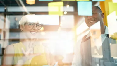 Colleagues at glass board with sticky notes