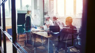 Meeting in a room where four workers sit around a large table 