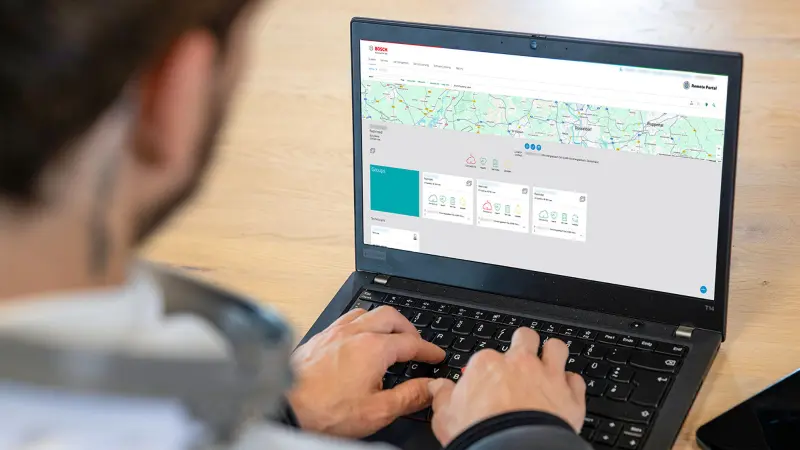 Person arbeitet an einem Laptop mit geöffneten Dashboard von Bosch Building Technologies.