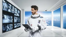 Person im Raumanzug steht in einem Video-Überwachungsraum.