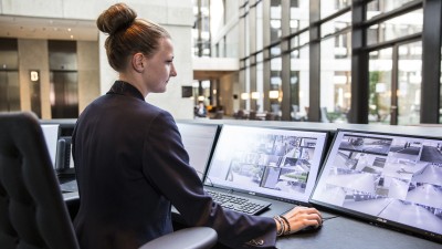 Frau an Rezeption, die auf Videoüberwachung schaut 