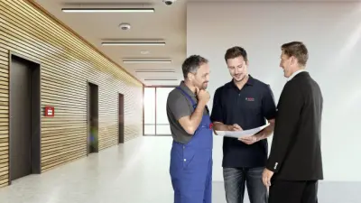 Drei Elektriker stehen zusammen und begutachten gemeinsam einen Plan.