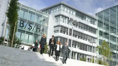 Menschen gehen vor dem Eingang der Firmenzentrale Treppen hinunter 