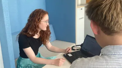 Romina steht lachend an einem Stehtisch mit ihrem Laptop, im Hintergrund ein Bild von Robert Bosch