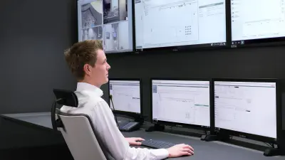 Person sitting in front of screens in control room